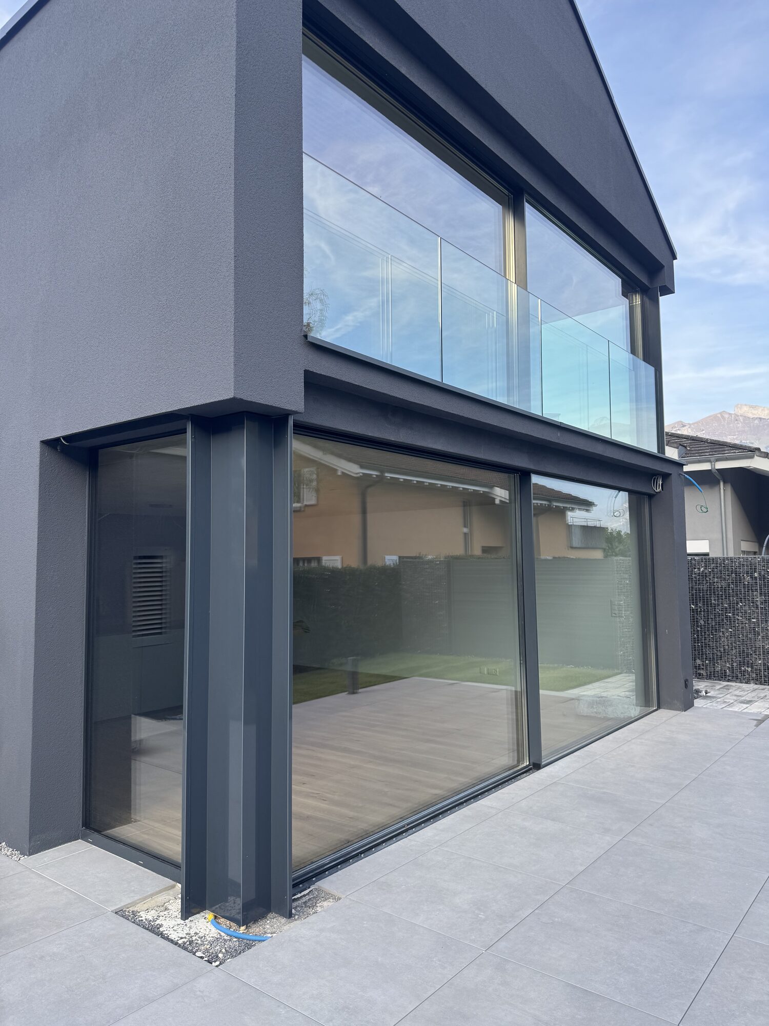 Façade contemporaine sombre avec grandes baies vitrées